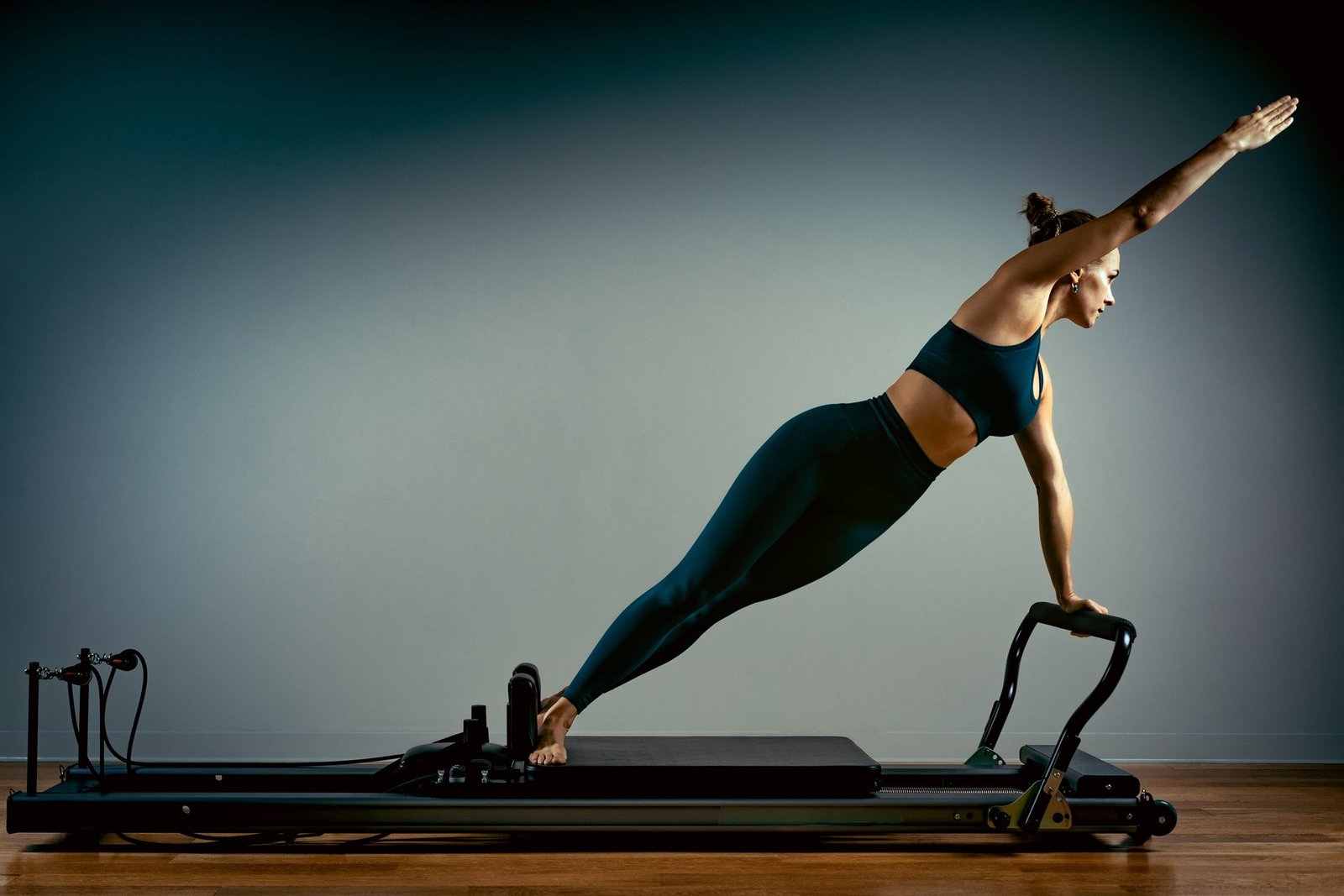 Mulher em posição de prancha sobre o reformer, em um estúdio de Pilates